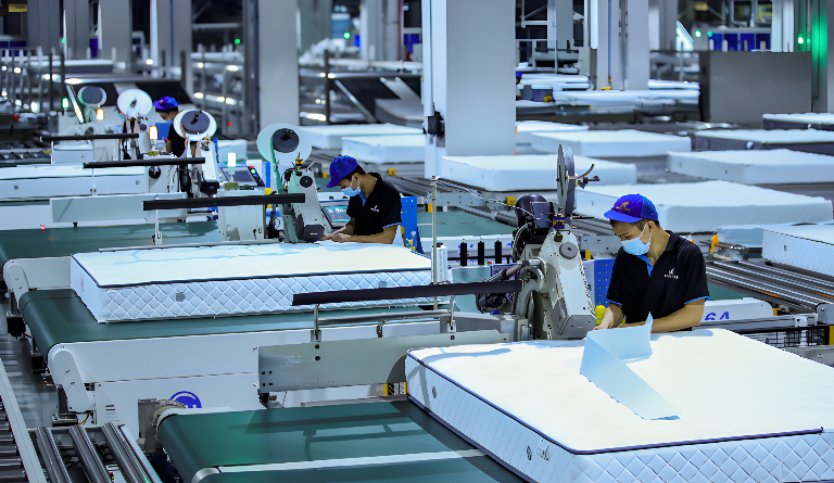 Opérateurs sur une ligne automatisée de fabrication de matelas dans une usine moderne, illustrant le pilotage de projets industriels par Bestlead, spécialiste du management de transition et de l’amélioration de la performance opérationnelle.