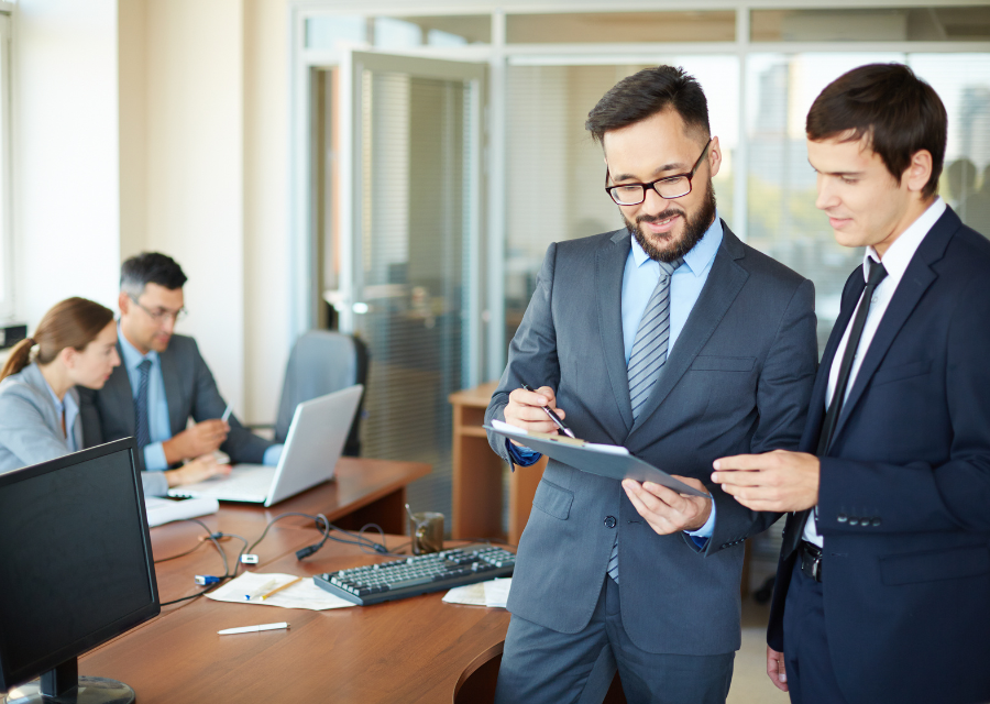 Managers en costumes travaillant en équipe autour d’un bureau, illustrant le management de transition, la direction de projet et l’accompagnement du changement en entreprise par Bestlead.